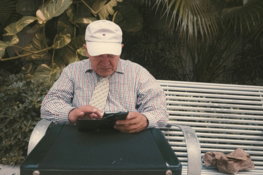 a-man-sitting-on-a-bench-looking-at-his-cell-phone.jpg a man sitting on a bench looking at his cell phone